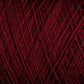 Close-up view of a tightly wound ball of deep red JaggerSpun Superfine Merino 2/18 Yarn from Jagger Brothers, Inc. The threads are intricately interwoven, creating a textured pattern with varying shades of red due to the light and shadow. The image emphasizes the fibrous and detailed nature of this hand knitters yarn.