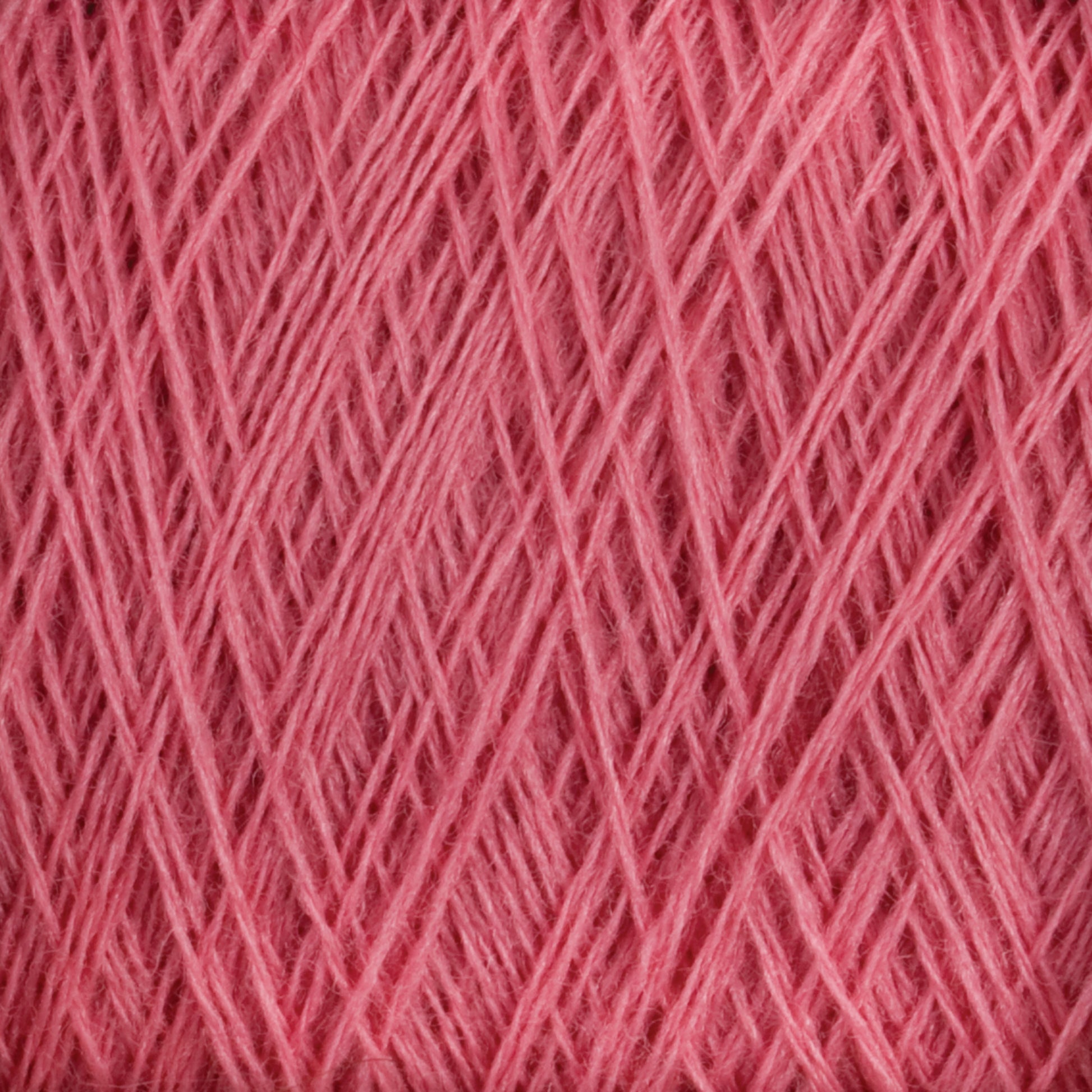 Close-up image of JaggerSpun Superfine Merino 2/18 Yarn | Mini-cone by Jagger Brothers, Inc., showcasing the pink worsted spun Merino wool yarn with tightly wound fibers in a crisscross pattern, creating a textured and detailed view of the material. The yarn appears soft and slightly fuzzy.