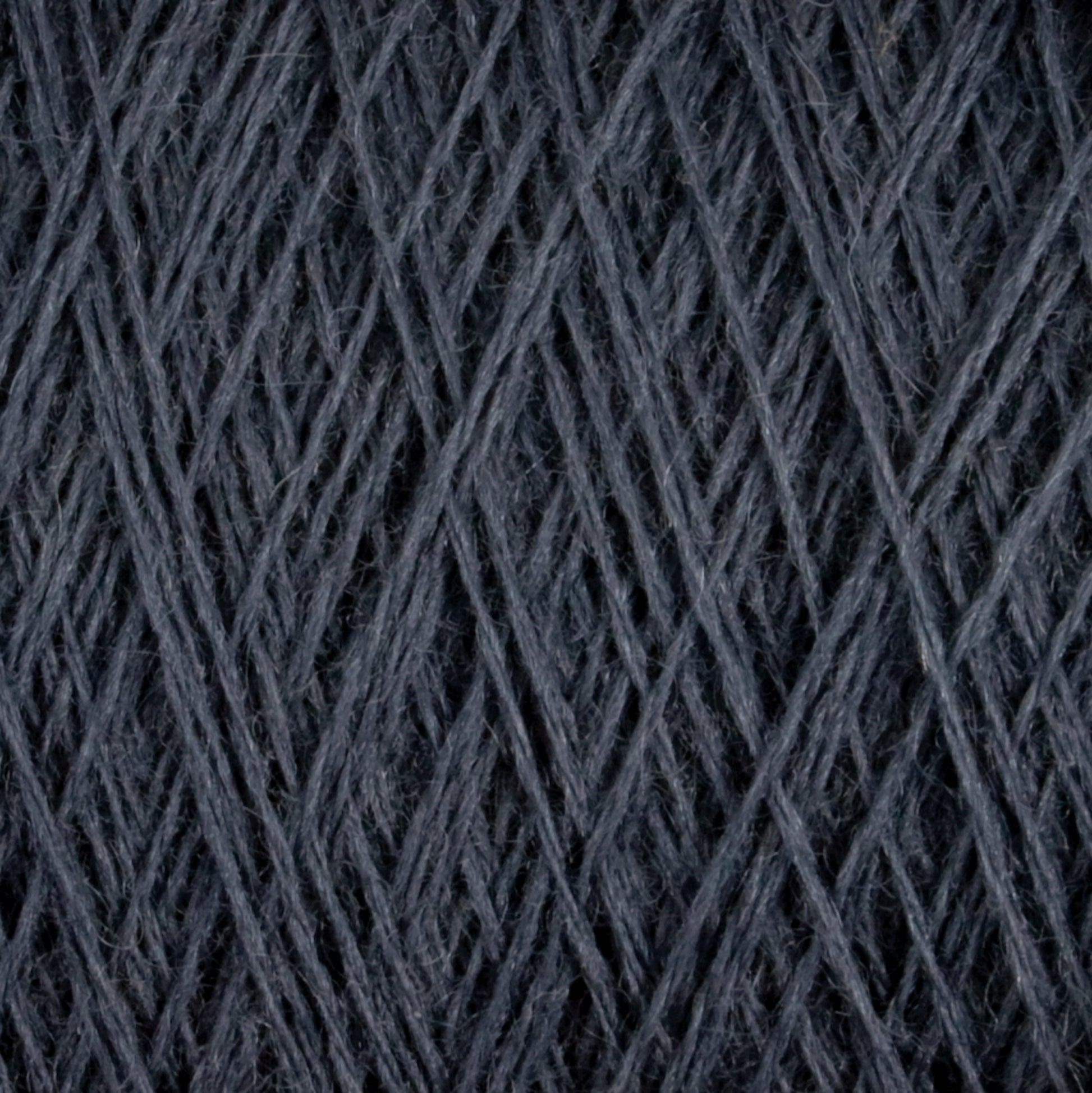 Close-up image of dark grey JaggerSpun Superfine Merino 2/18 Yarn by Jagger Brothers, Inc., wound tightly in a mini-cone, showcasing the intricate crisscross pattern of the fibers. The texture appears soft and slightly fuzzy, highlighting the fibrous nature of this hand knitters yarn.