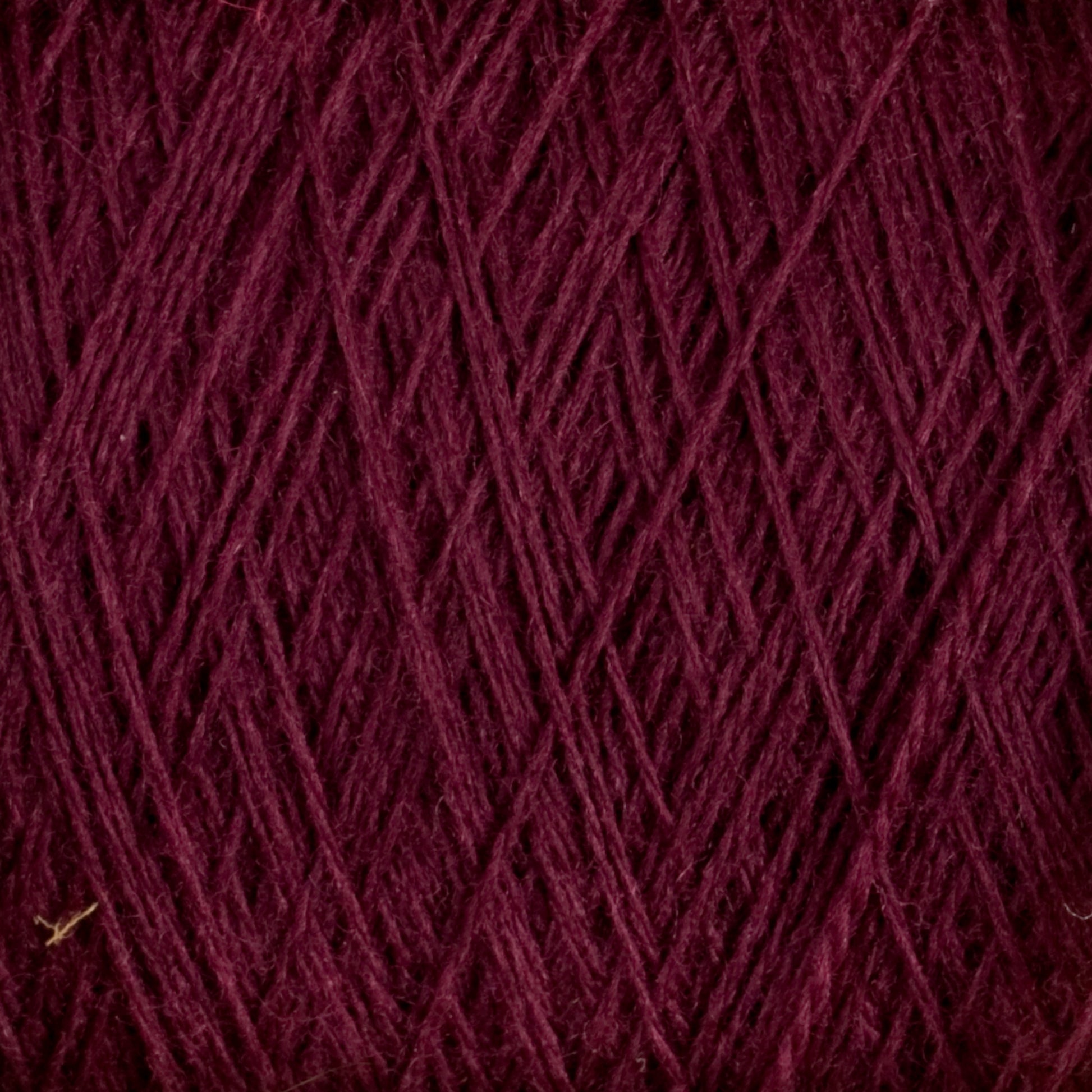 Close-up of the JaggerSpun Superfine Merino 2/18 Yarn | Mini-cone in burgundy, revealing a crisscross pattern. The image displays the texture and details of the tightly woven strands, with the rich, dark red color dominating the view. Ideal for hand knitters, this worsted spun yarn from Jagger Brothers, Inc. offers both beauty and durability.