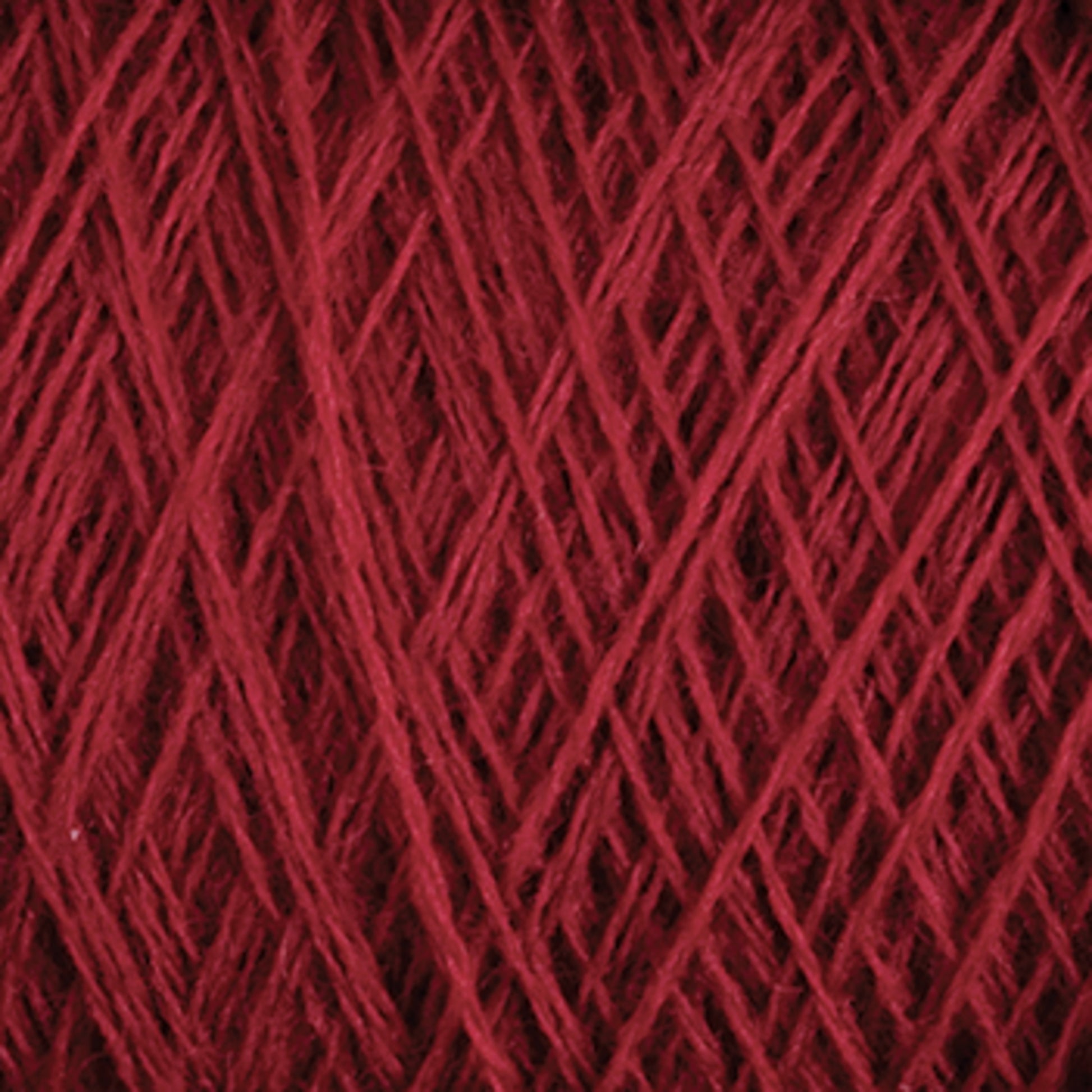 Close-up image of luxurious deep red JaggerSpun Zephyr Wool-Silk 2/18 Yarn wound tightly in a ball, showing the texture and fibrous strands intertwined in a crisscross pattern from Jagger Brothers, Inc.