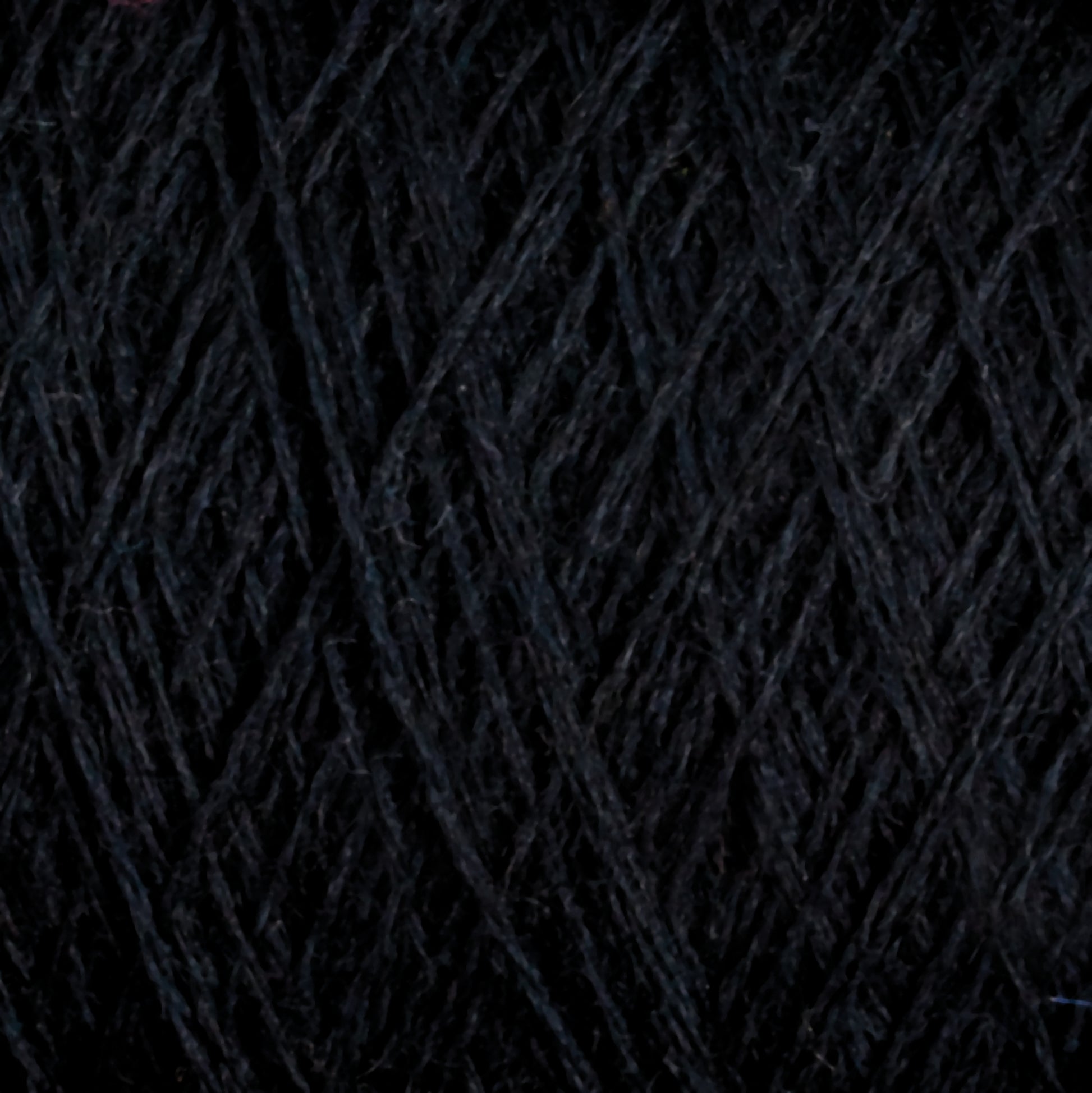 Close-up of JaggerSpun Zephyr Wool-Silk 2/18 Yarn by Jagger Brothers, Inc., showcasing its black yarn with a visible texture and interwoven strands forming a crisscross pattern. The slightly fuzzy surface highlights the luxurious fibrous nature of this premium blend, combining fine silk with Australian merino wool for unparalleled softness and quality in this large cone format.