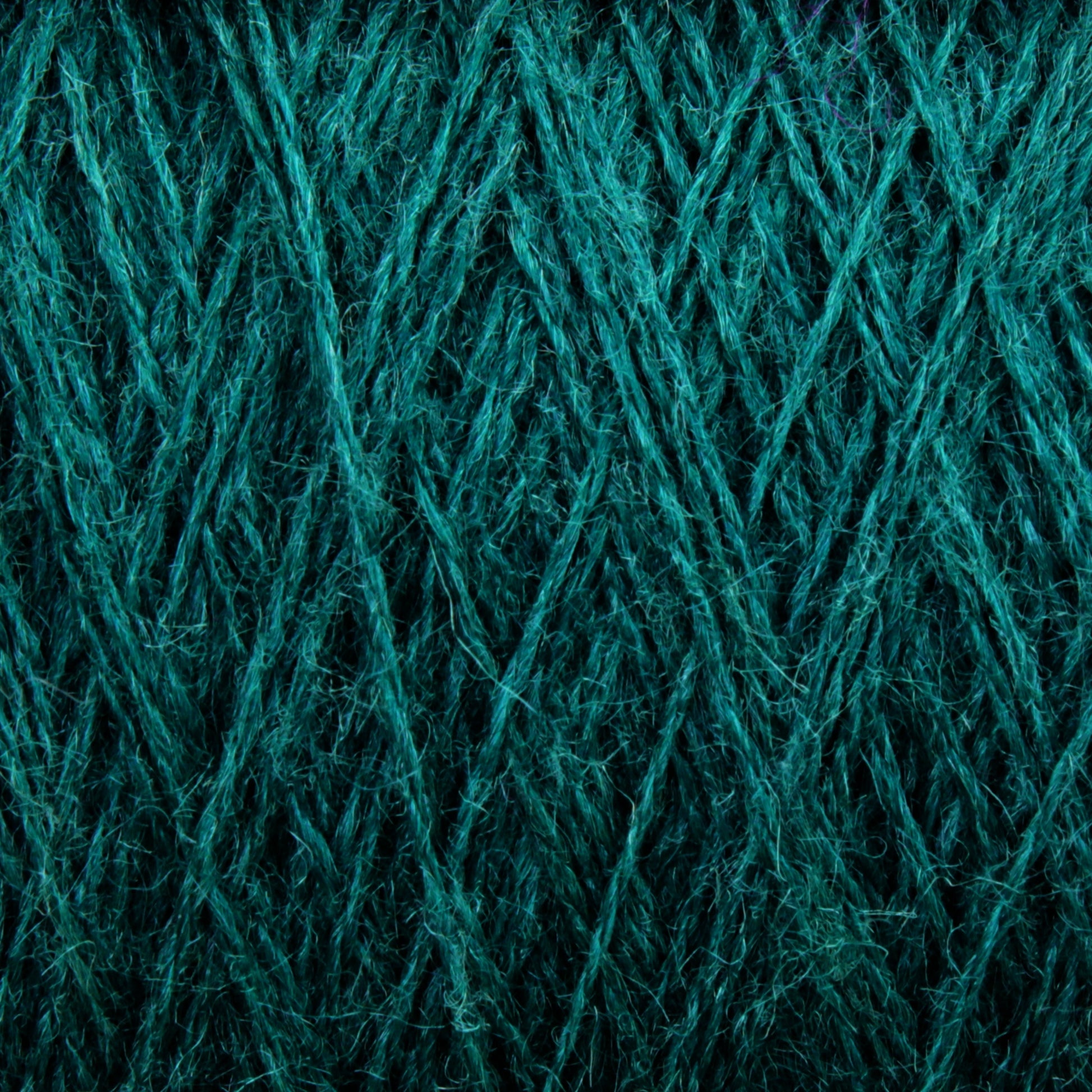 Close-up of the intricate texture of a teal-colored JaggerSpun Zephyr Wool-Silk 2/18 Yarn | Mini-cone by Jagger Brothers, Inc. The fibers are tightly woven with crisscrossing patterns, creating a rich, detailed surface. The vibrant color enhances the texture, making this luxurious yarn appear both soft and sturdy.