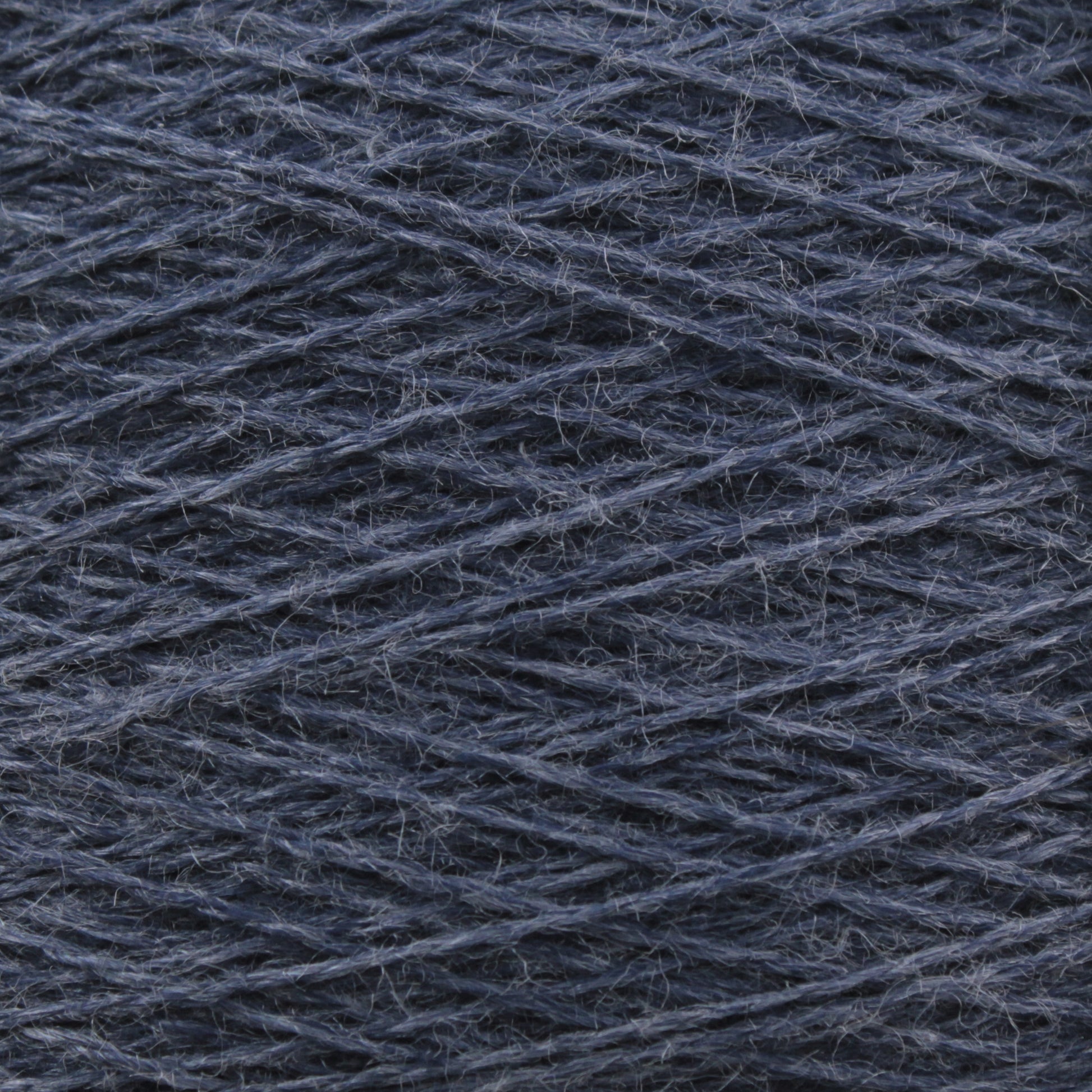 A close-up view of a mini-cone of JaggerSpun Zephyr Wool-Silk 2/18 Yarn by Jagger Brothers, Inc., revealing the intricate texture and fibers of luxurious dark blue Australian superfine merino wool intertwining in a crisscross pattern.