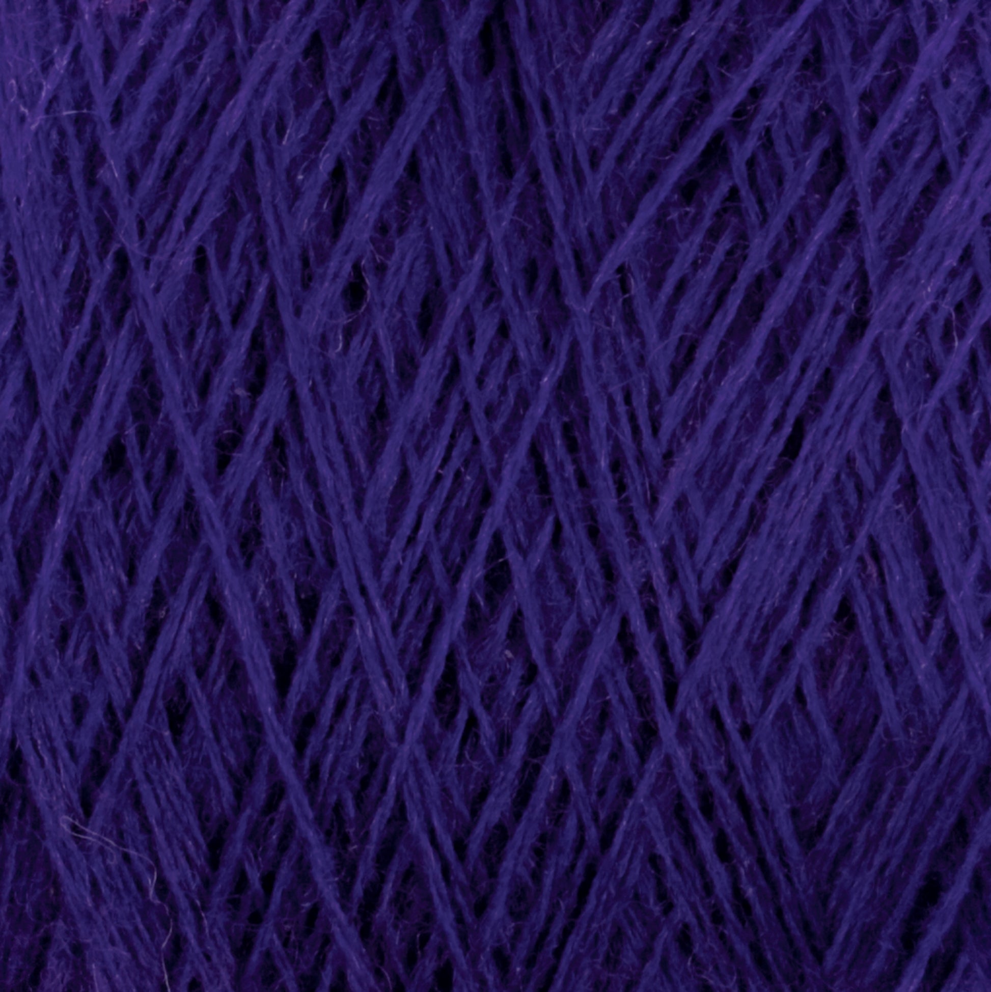 Close-up image of JaggerSpun Zephyr Wool-Silk 2/18 Yarn in deep purple. The luxurious strands from Jagger Brothers, Inc. are tightly wound and crisscrossing in various directions, creating an intricate and textured pattern. The yarn appears soft and dense, making it suitable for knitting or crocheting projects.