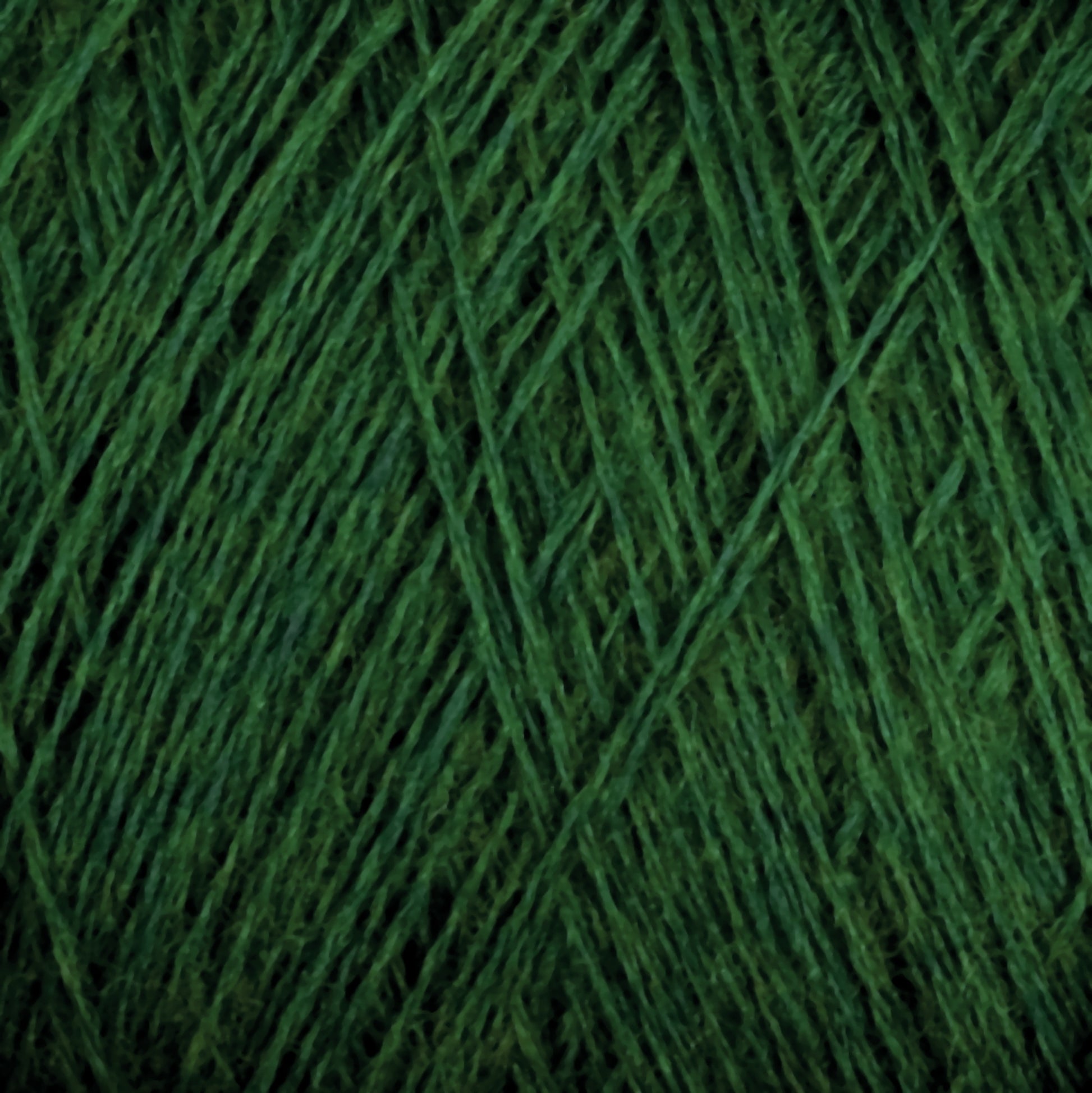 Close-up image of the luxurious JaggerSpun Zephyr Wool-Silk 2/18 Yarn by Jagger Brothers, Inc., showcasing its intricate crisscrossing fibers and texture. The yarn appears thick and tightly wound, with a rich, deep green hue.