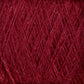 Close-up of a ball of deep red, luxurious JaggerSpun Zephyr Wool-Silk 2/18 Yarn from Jagger Brothers, Inc. The fibers are tightly wound, and the texture appears soft and fuzzy with a rich and vibrant color. The intricate crisscrossing pattern of the strands is visible, showcasing the yarn's consistent thickness and evenness, reminiscent of premium silk.