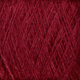 Close-up of a ball of deep red, luxurious JaggerSpun Zephyr Wool-Silk 2/18 Yarn from Jagger Brothers, Inc. The fibers are tightly wound, and the texture appears soft and fuzzy with a rich and vibrant color. The intricate crisscrossing pattern of the strands is visible, showcasing the yarn's consistent thickness and evenness, reminiscent of premium silk.