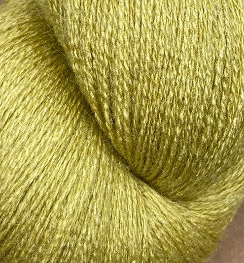 Close-up of a skein of JaggerSpun Zephyr Wool-Silk 2/18 Yarn in light green. The luxurious yarn by Jagger Brothers, Inc. has a fuzzy texture with a subtle shine, suggesting a soft and possibly premium silk blend. The tightly wound strands emphasize the yarn's high quality and fine detail.