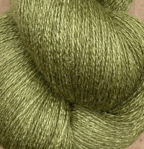 A close-up view of a skein of light olive green JaggerSpun Zephyr Wool-Silk 2/18 Yarn from Jagger Brothers, Inc., showcasing its luxurious, soft, and slightly fuzzy texture.