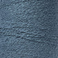 A close-up image of a spool of Maurice Brassard Cotton Bouclé Yarn. The yarn, tightly wound on a tube, exhibits visible fibers and slight irregularities that enhance its textured appearance. The muted, cool blue color of the yarn suggests a soft and cozy material ideal for creating Maurice Brassard weavings.