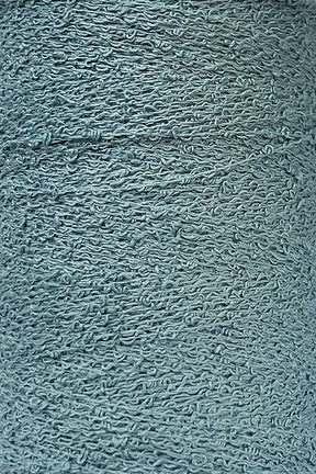 Close-up of a textured grey surface showing numerous intertwined, wave-like patterns. The material appears to be rough and fibrous, reminiscent of Maurice Brassard's intricate Cotton Bouclé Yarn, suggesting it could be a detailed portion of fabric or another textured synthetic material.