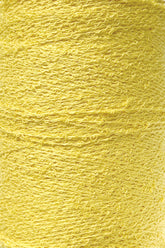 Close-up shot of a spool of vibrant yellow Cotton Bouclé Yarn | Tube by Maurice Brassard. The texture is clearly visible, showcasing its tightly wound, slightly curly threads.