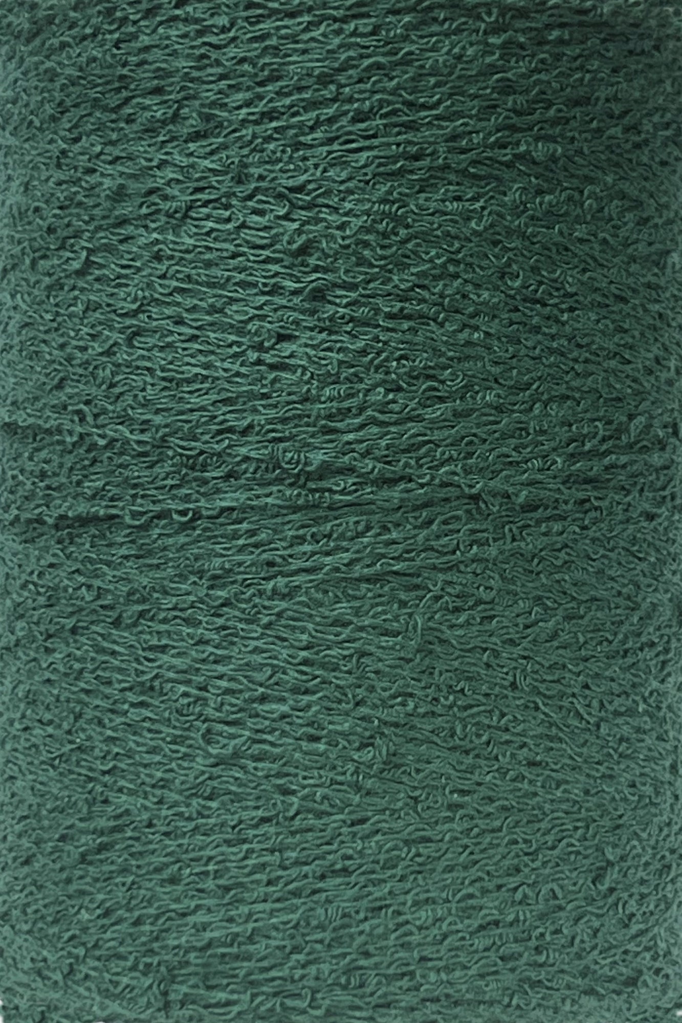 A close-up image of a spool of Maurice Brassard Cotton Bouclé Yarn | Mini-Cone in forest green. The texture of the 100% cotton yarn is visible, showcasing its tightly woven strands. The overall appearance is uniform in color and texture, with slight variations on the surface due to the fibrous material.