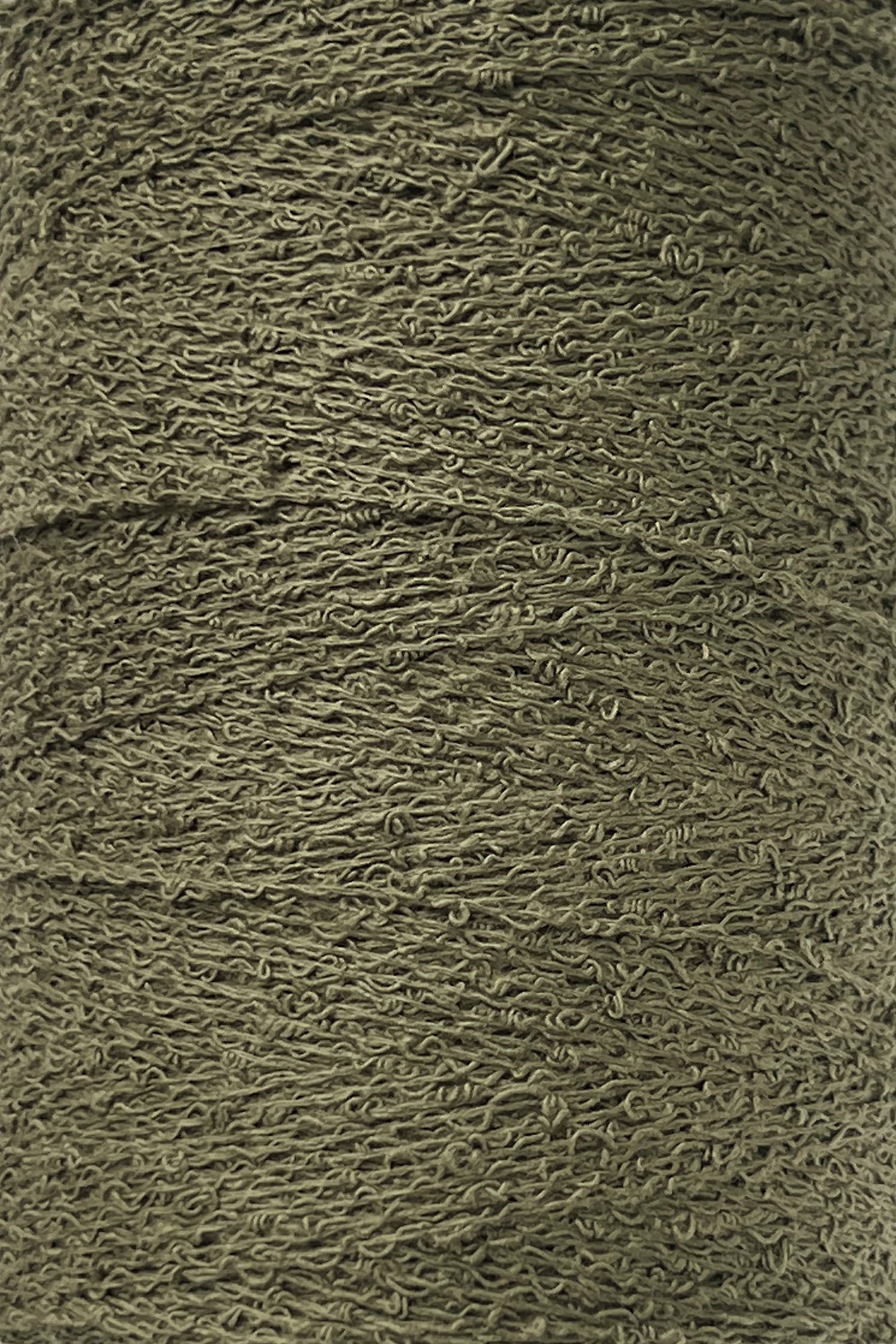 Close-up image of a spool of Maurice Brassard Cotton Bouclé Yarn. The texture of the weaving cotton is visible, showcasing the fine fibers tightly wound around the tube. The yarn appears smooth and uniform in thickness.