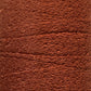 Close-up image of a spool of reddish-brown yarn with a textured, slightly wavy appearance. The densely wound Maurice Brassard Cotton Bouclé Yarn | Tube showcases intricate and uniform layers throughout.