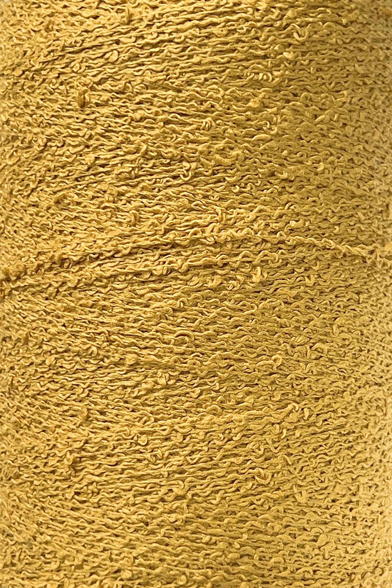 Close-up image of a spool of textured golden yellow Cotton Bouclé Yarn | Tube by Maurice Brassard, showcasing its detailed, rough surface. The tightly wound yarn forms an intricate pattern of loops and twists throughout the spool, making it perfect for weaving cotton projects.