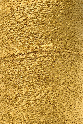 Close-up image of a spool of textured golden yellow Cotton Bouclé Yarn | Tube by Maurice Brassard, showcasing its detailed, rough surface. The tightly wound yarn forms an intricate pattern of loops and twists throughout the spool, making it perfect for weaving cotton projects.