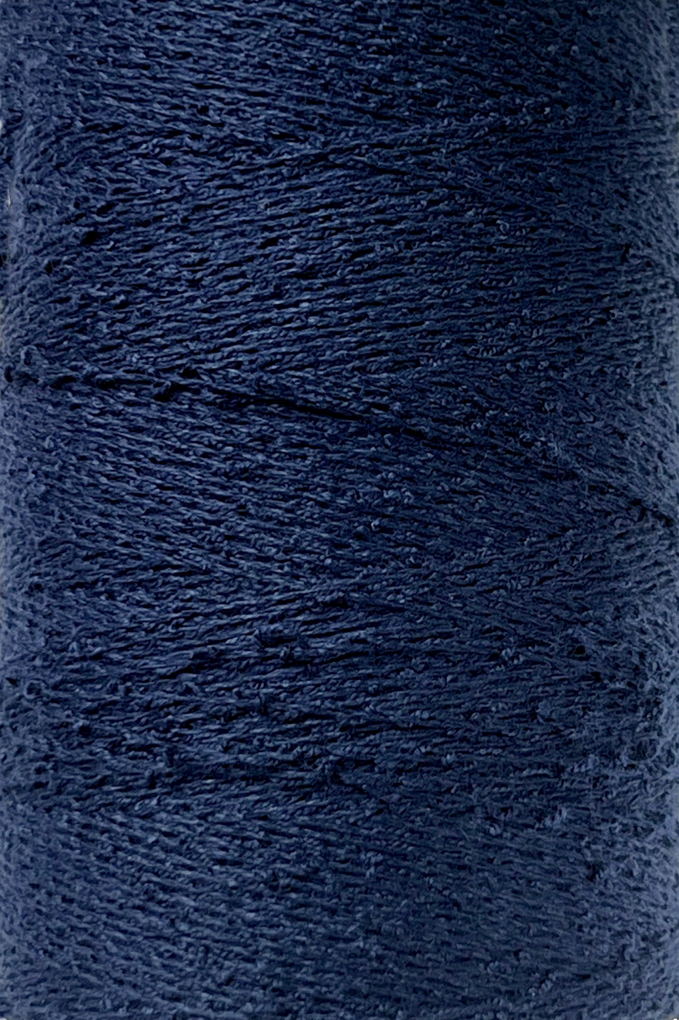 Close-up image of a spool of Maurice Brassard's Cotton Bouclé Yarn in dark navy blue. The texture of the yarn is clearly visible, showcasing a tightly wound, slightly uneven surface. This creation appears thick and sturdy, perfect for intricate weaving projects.