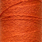 Close-up of a bright orange spool of Cotton Bouclé Yarn | Tube from Maurice Brassard, featuring a rough texture. This tightly wound yarn, ideal for weaving cotton projects, highlights its fibrous details and rich color reminiscent of those from the esteemed Maurice Brassard collections.