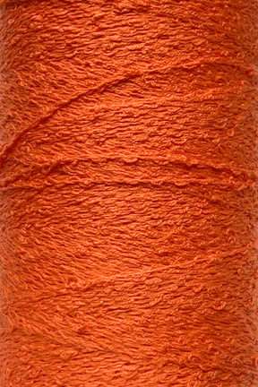 Close-up of a bright orange spool of Cotton Bouclé Yarn | Tube from Maurice Brassard, featuring a rough texture. This tightly wound yarn, ideal for weaving cotton projects, highlights its fibrous details and rich color reminiscent of those from the esteemed Maurice Brassard collections.