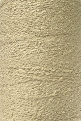 Close-up image of a spool of Maurice Brassard Cotton Bouclé Yarn | Tube. The yarn features a beige, textured surface with noticeable loops and knots, giving it a bumpy and irregular appearance. The fibers look soft and fluffy, tightly wound into a cylindrical shape. Ideal for weaving enthusiasts who value the quality offered by Maurice Brassard.