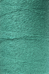 Close-up image of a spool of Maurice Brassard's Cotton Bouclé Yarn | Tube. The surface appears wavy and rough, with intricate loops and twists throughout, creating a detailed, tactile pattern. The color is a solid, vibrant green. Ideal for weaving projects by artisans who appreciate high-quality cotton materials.