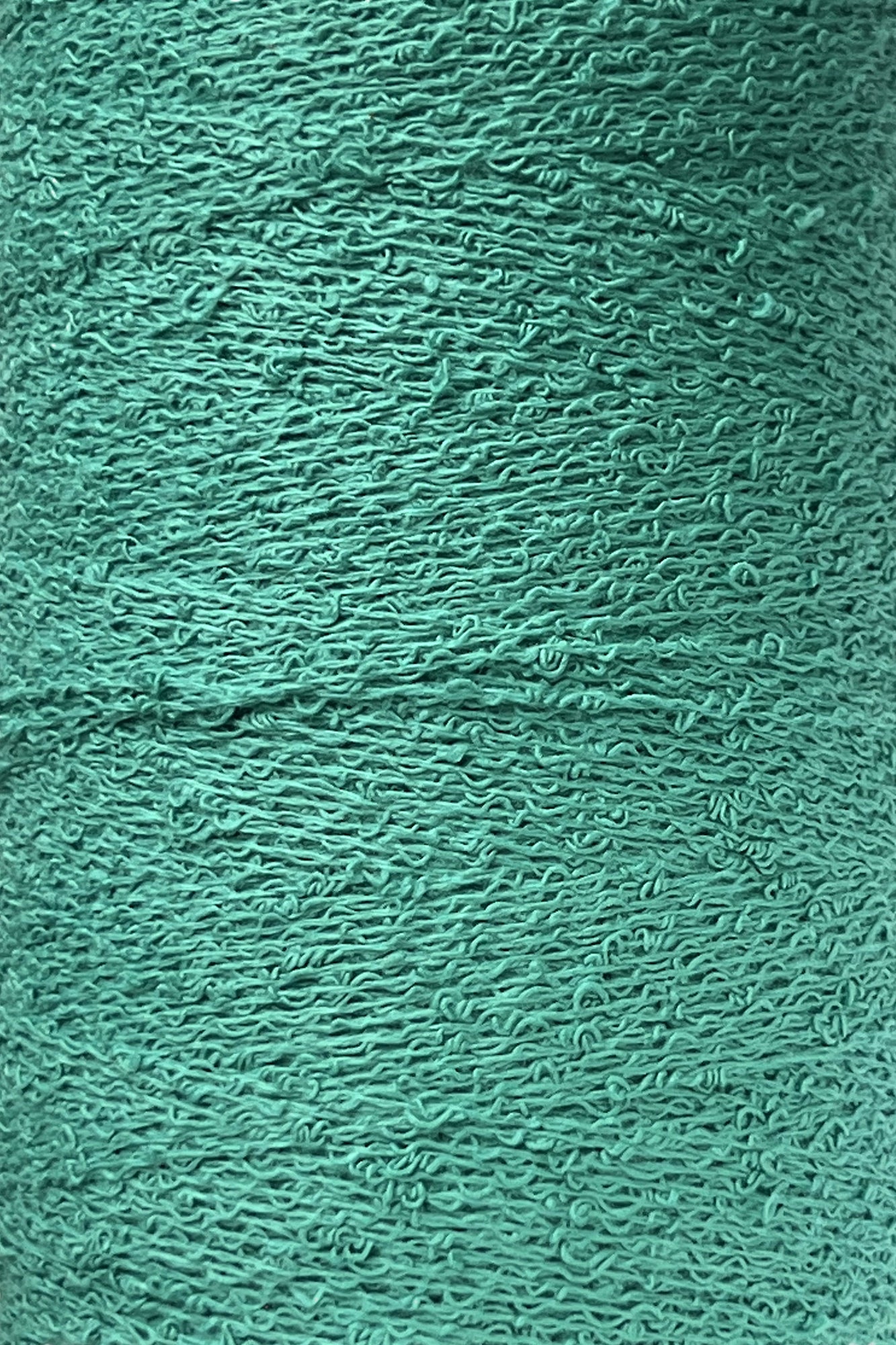 Close-up of a mini-cone of Maurice Brassard's Cotton Bouclé Yarn in teal. The strands are tightly wound together, creating a uniformly dense appearance with slight variations and grooves visible on the surface. This 100% cotton yarn boasts a slightly rough, wavy texture.