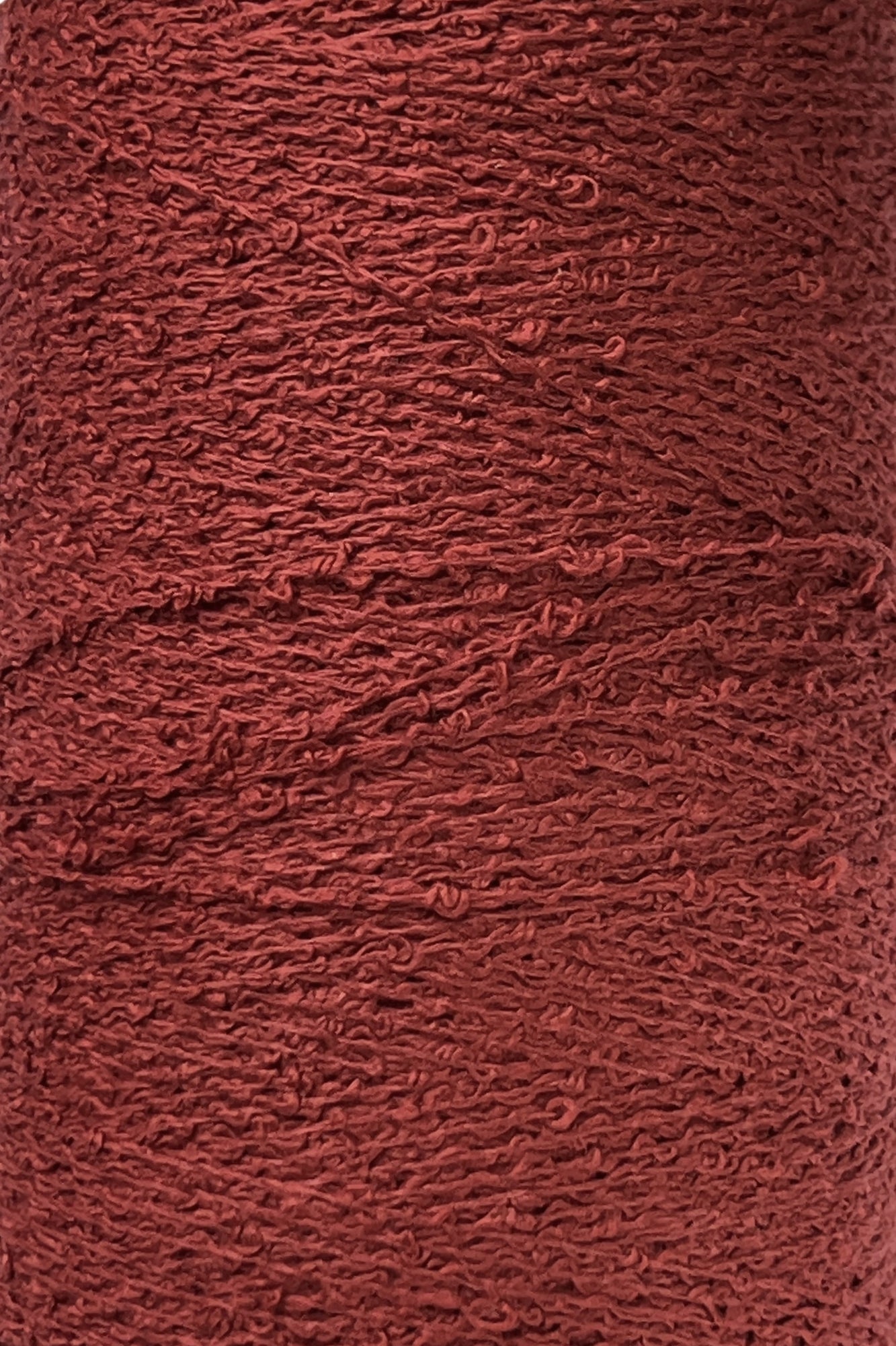 Close-up of a spool of Maurice Brassard Cotton Bouclé Yarn | Tube, featuring its textured, reddish-brown fibers with a slightly rough and uneven surface. The yarn boasts a semi-matte finish and appears tightly wound, showcasing visible twists and loops in the strands.