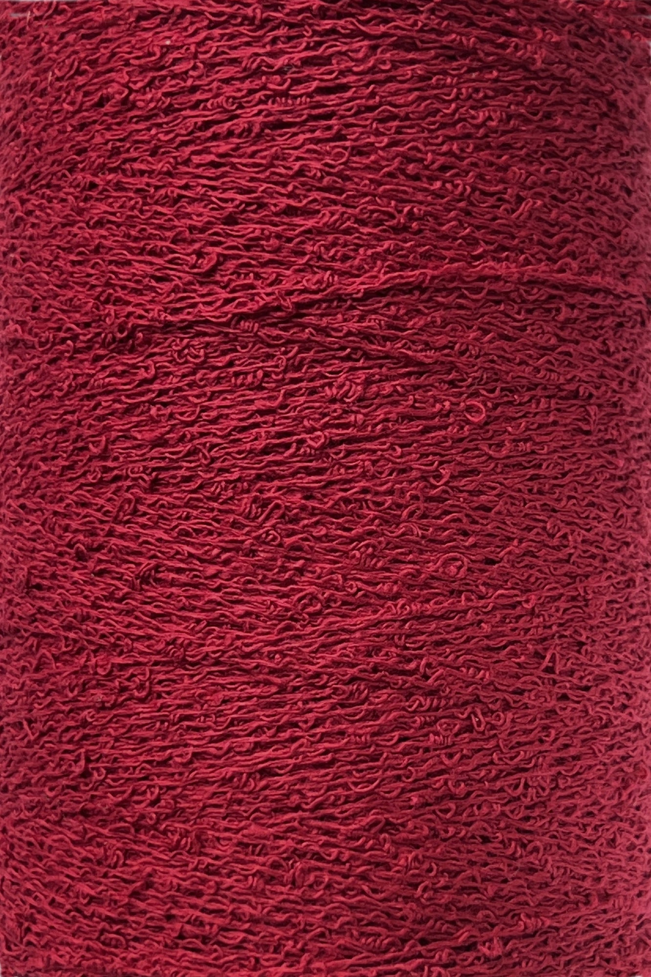 Close-up of a large spool of vibrant red yarn. Tightly wound, this 100% Cotton Bouclé Yarn | Mini-Cone from Maurice Brassard features a slightly crimped texture, creating an intricate, wavy surface pattern. The color is consistent throughout the spool, making it ideal for weaving cotton projects.