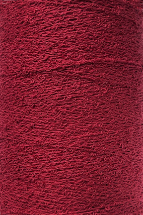 Close-up of a large spool of vibrant red yarn. Tightly wound, this 100% Cotton Bouclé Yarn | Mini-Cone from Maurice Brassard features a slightly crimped texture, creating an intricate, wavy surface pattern. The color is consistent throughout the spool, making it ideal for weaving cotton projects.