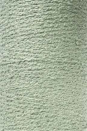 Close-up image of a spool of light green Cotton Bouclé Yarn from Maurice Brassard. The yarn, available in a Mini-Cone, is 100% cotton with a slightly rough, uneven surface featuring noticeable twists and loops throughout, indicating a natural or hand-spun quality. Its overall appearance is soft and fibrous, perfect for weaving enthusiasts.