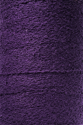 Close-up shot of a tightly wound spool of Maurice Brassard's Cotton Bouclé Yarn in purple. The slightly rough surface of this weaving yarn appears dense, with layers stacked consistently in a continuous pattern.