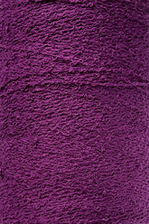 A close-up image of tightly-wound deep purple yarn. The texture and individual strands are visible, showcasing the intricate pattern reminiscent of Maurice Brassard's Cotton Bouclé Yarn | Tube.