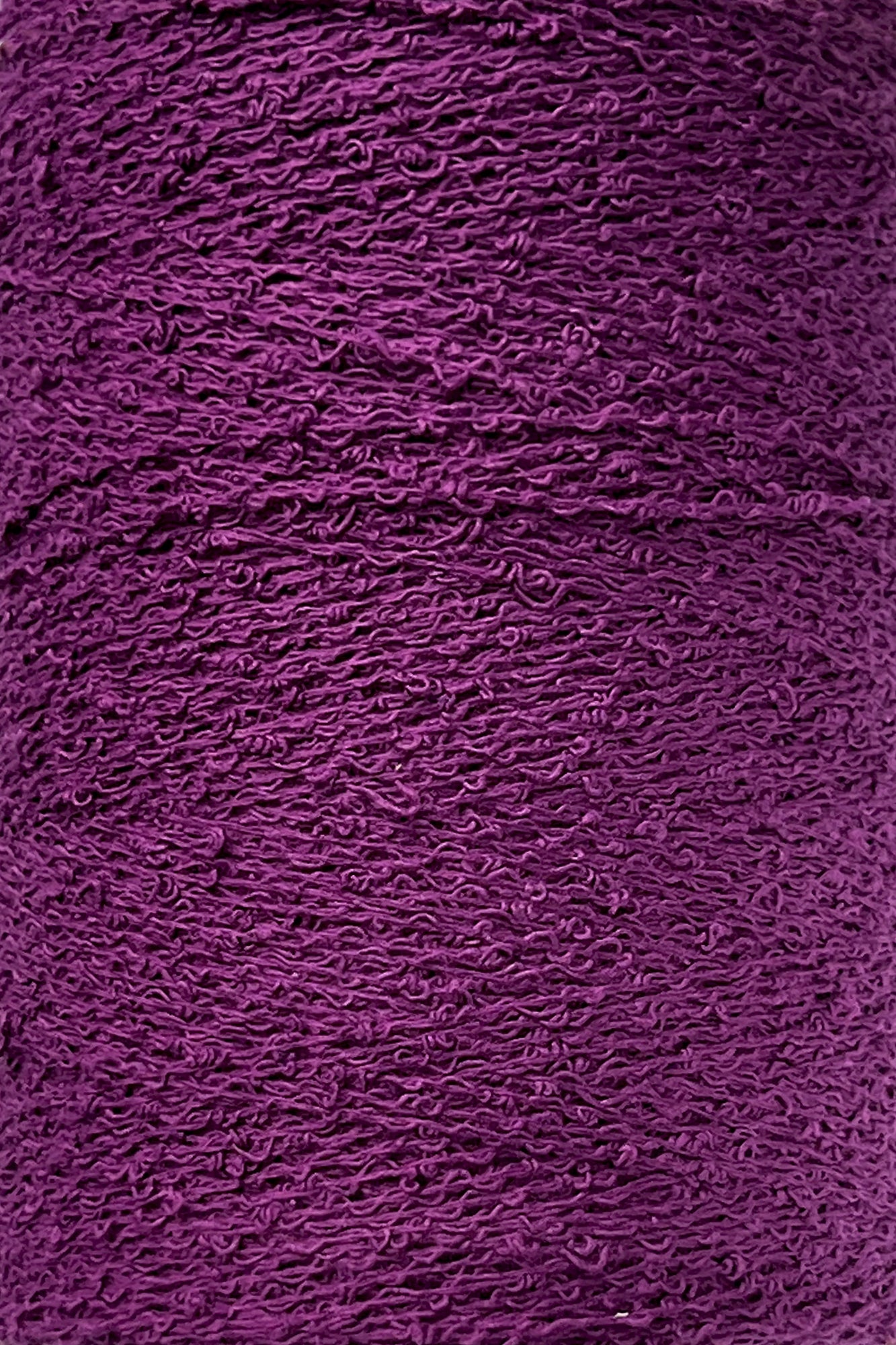 A close-up image of tightly-wound deep purple yarn. The texture and individual strands are visible, showcasing the intricate pattern reminiscent of Maurice Brassard's Cotton Bouclé Yarn | Tube.