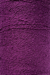 Close-up image of a tightly wound spool of Maurice Brassard's Cotton Bouclé Yarn | Mini-Cone in purple, showcasing its fibrous and textured surface. Made from 100% cotton bouclé, the yarn appears soft and slightly wavy, forming a dense, continuous pattern perfect for weaving cotton projects.