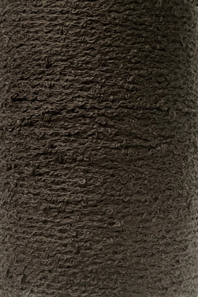 A close-up image of a dark brown textured fabric reveals a tightly woven pattern with visible fibers and a slightly rough surface, reminiscent of the Cotton Bouclé Yarn | Tube by Maurice Brassard.