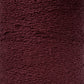 A close-up image of a large spool of dark red or maroon textured yarn. The yarn appears thick and tightly wound, with a somewhat rough, looped surface. The image captures the detailed texture of the woven fibers, showcasing Maurice Brassard's Cotton Bouclé Yarn | Mini-Cone, perfect for weaving cotton projects.