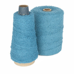 Two cones of Maurice Brassard Cotton Bouclé Yarn | Tube are shown, one slightly shorter and tapered, the other taller and cylindrical. Both cones are wound with textured blue yarn and stand side by side on a white background.