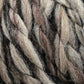 Close-up of thick Bear Creek Yarn by Kraemer strands in various shades of beige, brown, and gray entwined together. The texture appears soft and woolly, with individual fibers visibly interwoven, creating a rich and natural look perfect for handknits.