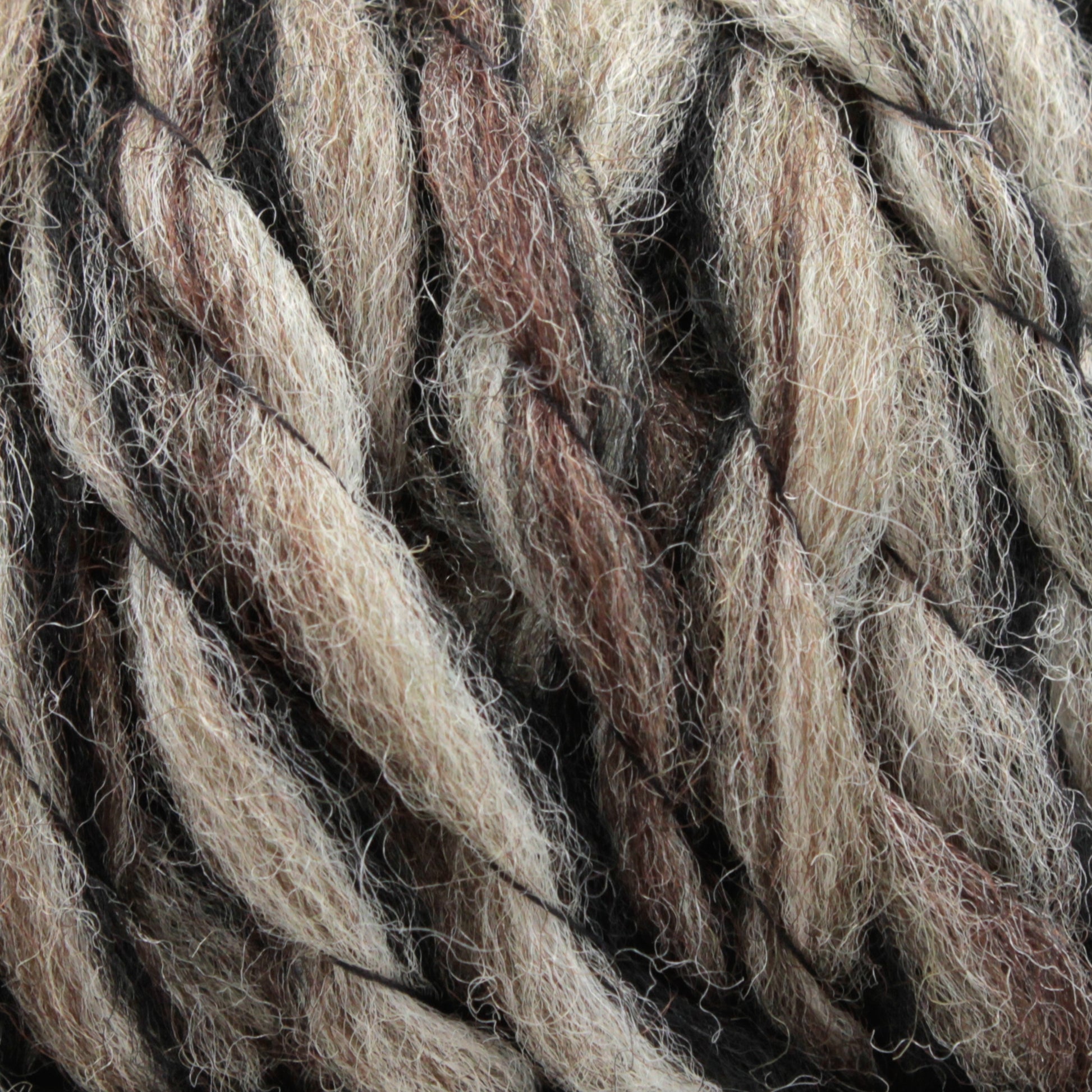 Close-up of thick Bear Creek Yarn by Kraemer strands in various shades of beige, brown, and gray entwined together. The texture appears soft and woolly, with individual fibers visibly interwoven, creating a rich and natural look perfect for handknits.