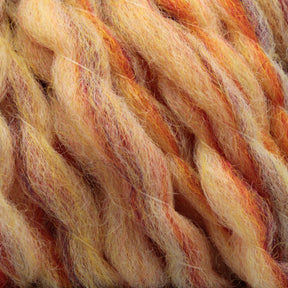 Close-up image of twisted, multicolored Bear Creek Yarn by Kraemer with shades of yellow, orange, and red. The super bulky yarn appears soft and fluffy, showcasing thick and textured fiber. The blending of colors gives it a warm, vibrant, autumnal feel, perfect for cozy domestic wool handknits.