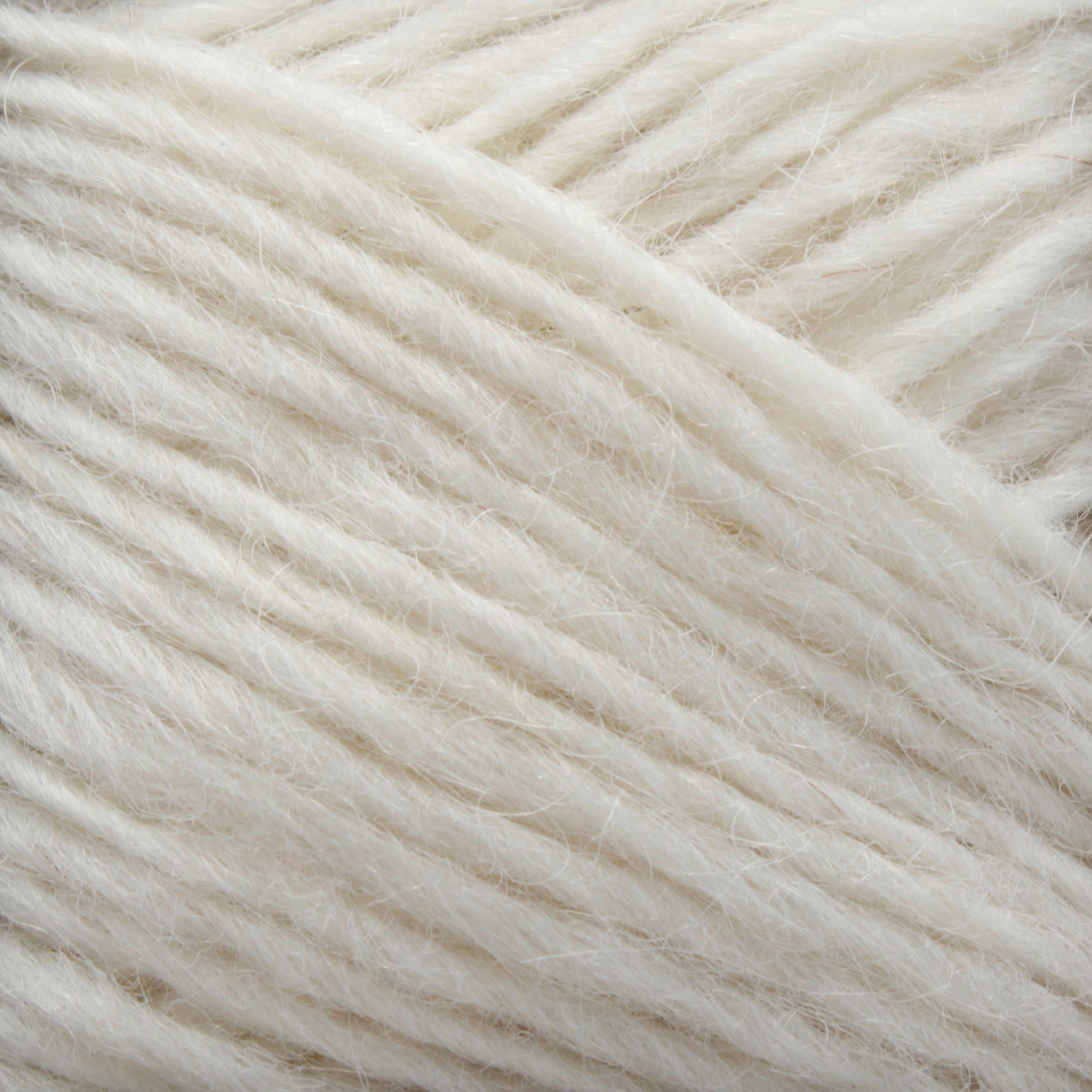 Close-up image of a section of Léttlopi (Lite Lopi) Icelandic Wool Yarn by Berroco, Inc. The soft fibers are loosely twisted and have a slightly fluffy, textured appearance. This off-white Icelandic wool showcases its natural, creamy color and smooth, yet fibrous surface—an ideal choice for durable garments or intricate colorwork knitting projects.