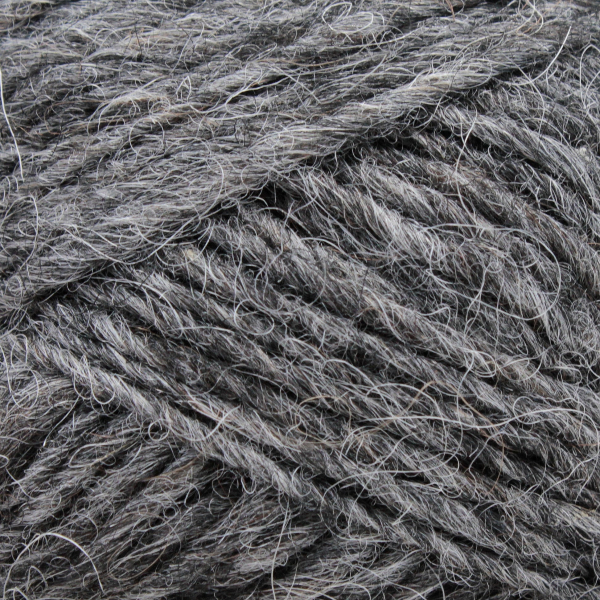 Close-up image of Berroco, Inc.'s Léttlopi (Lite Lopi) Icelandic Wool Yarn in grey, twisted into thick strands, showcasing a mix of smooth and stray fibers. The texture appears soft and slightly fuzzy, ideal for colorwork knitting or creating durable garments.