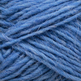 A close-up of Berroco, Inc.'s Léttlopi (Lite Lopi) Icelandic Wool Yarn showcases its soft, fibrous texture with various shades of blue intertwining. The image captures the intricate detail of the yarn's strands, highlighting its fluffy and slightly fuzzy appearance, ideal for durable garments or delicate colorwork knitting projects.