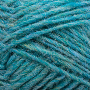 Close-up of a bundle of Léttlopi (Lite Lopi) Icelandic Wool Yarn in varying shades of teal and turquoise from Berroco, Inc. The fibers are slightly fuzzy, giving a soft and textured appearance. The yarn is wrapped loosely, showcasing its thickness and individual strands, perfect for colorwork knitting or durable garments.