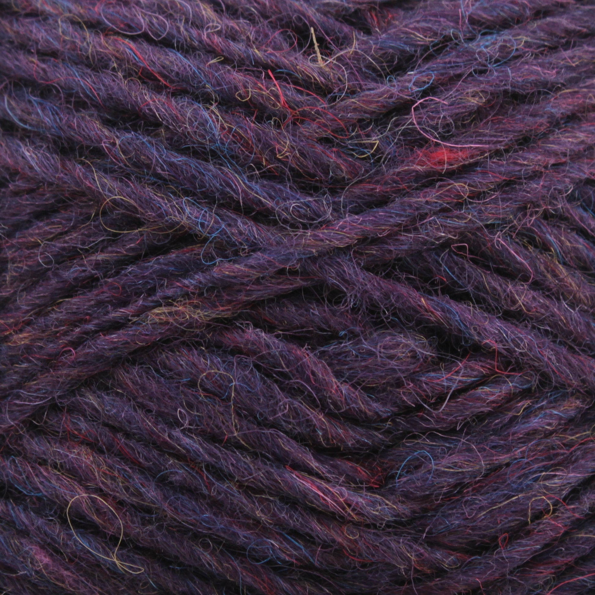 Close-up of dark purple Léttlopi (Lite Lopi) Icelandic wool yarn by Berroco, Inc., showcasing multiple twisted strands. The slightly rough texture includes subtle threads in shades of blue and red, creating a rich, multifaceted appearance perfect for durable garments and colorwork knitting projects.