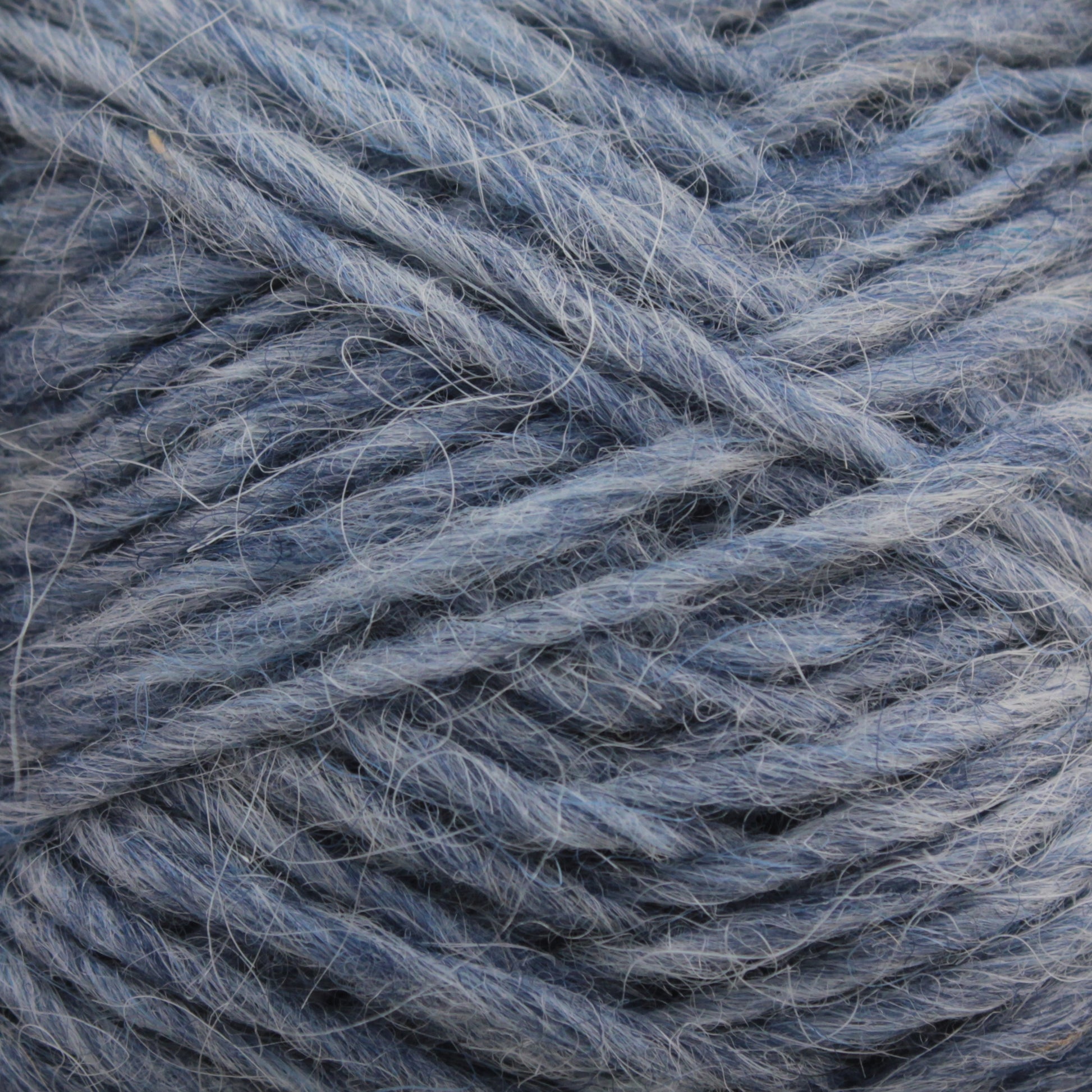 Close-up image of a ball of Berroco, Inc. Léttlopi (Lite Lopi) Icelandic Wool Yarn in blue. The fibers are thick and slightly tangled, with visible individual strands and a soft texture. The hue is a muted blue with subtle variations in shade, ideal for colorwork knitting or crafting durable garments.