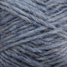 Close-up image of a ball of Berroco, Inc. Léttlopi (Lite Lopi) Icelandic Wool Yarn in blue. The fibers are thick and slightly tangled, with visible individual strands and a soft texture. The hue is a muted blue with subtle variations in shade, ideal for colorwork knitting or crafting durable garments.