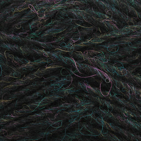 Close-up of a ball of dark, multicolored Léttlopi (Lite Lopi) Icelandic Wool Yarn from Berroco, Inc. with strands of green, blue, and purple interwoven. The texture is fuzzy and slightly irregular, making it perfect for creating durable garments that highlight the individual threads and fibers. Ideal for intricate colorwork knitting projects.